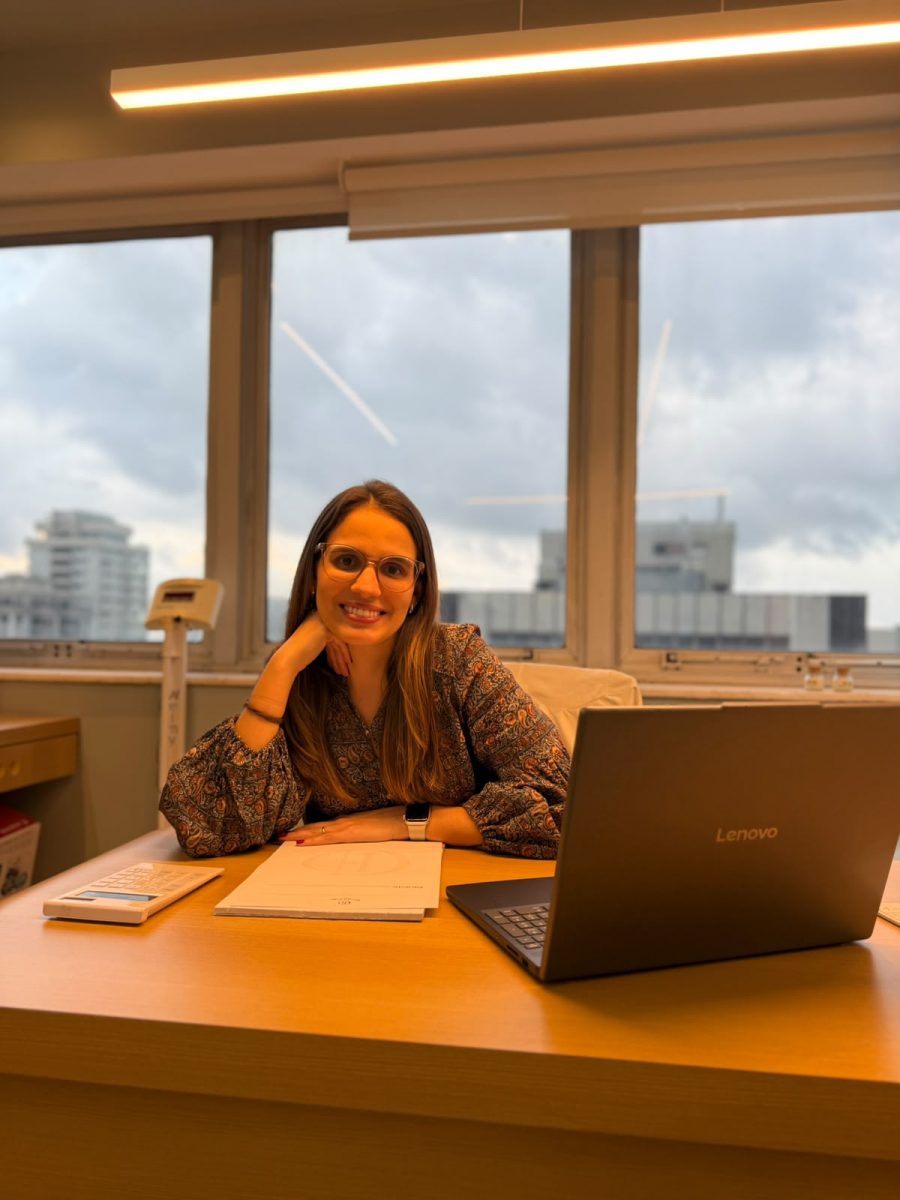 Dra. Gabriela Diogo, alergista e imunologista, sorrindo à mesa do consultório